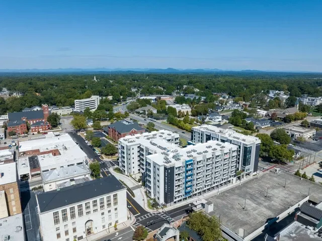Aerial view of the National Apartment Complex in Gainesville Georgia with diverse buildings, green trees, and clear blue sky in the background.