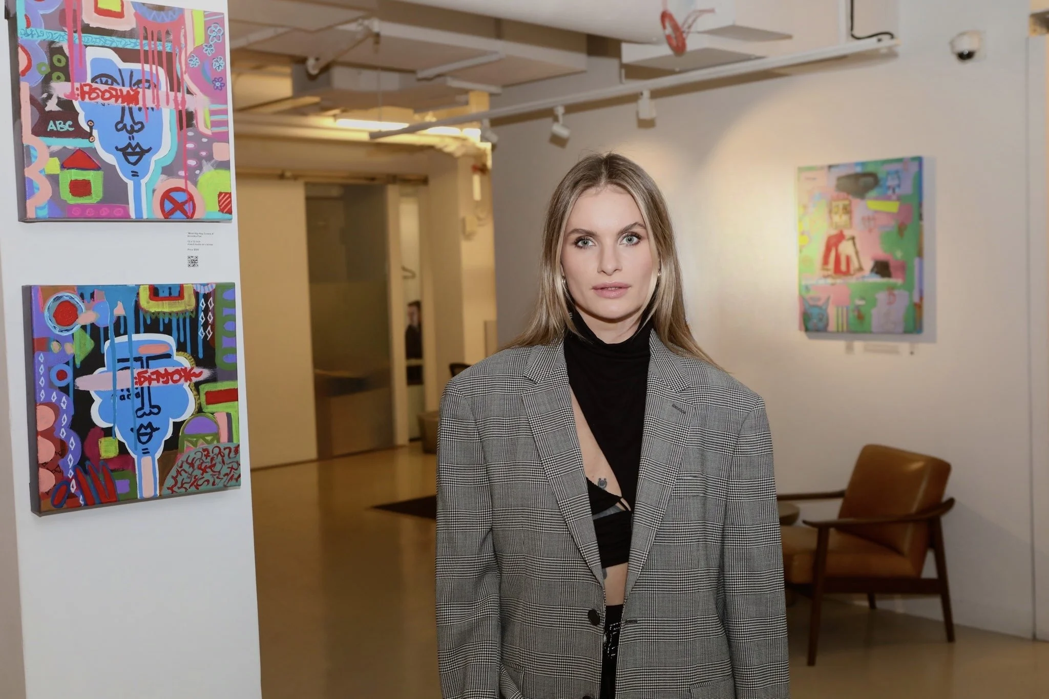 A young woman in an art gallery with colorful abstract paintings on the walls.