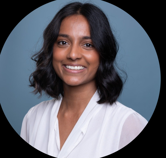 A woman with shoulder-length black hair smiling, wearing a white top, against a light blue background.