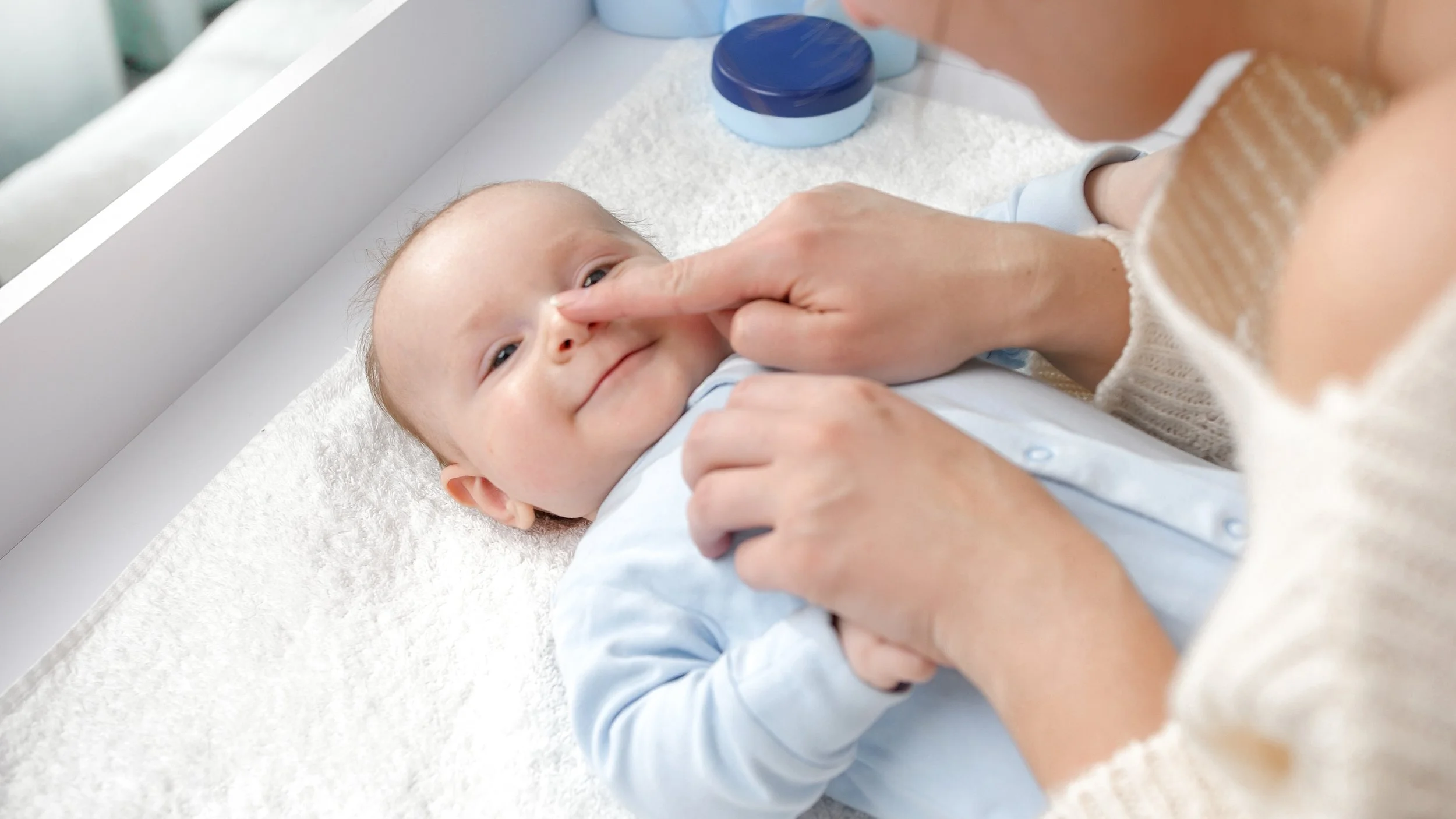 Newborn baby with gentle skincare essentials recommended by a pediatric dermatologist