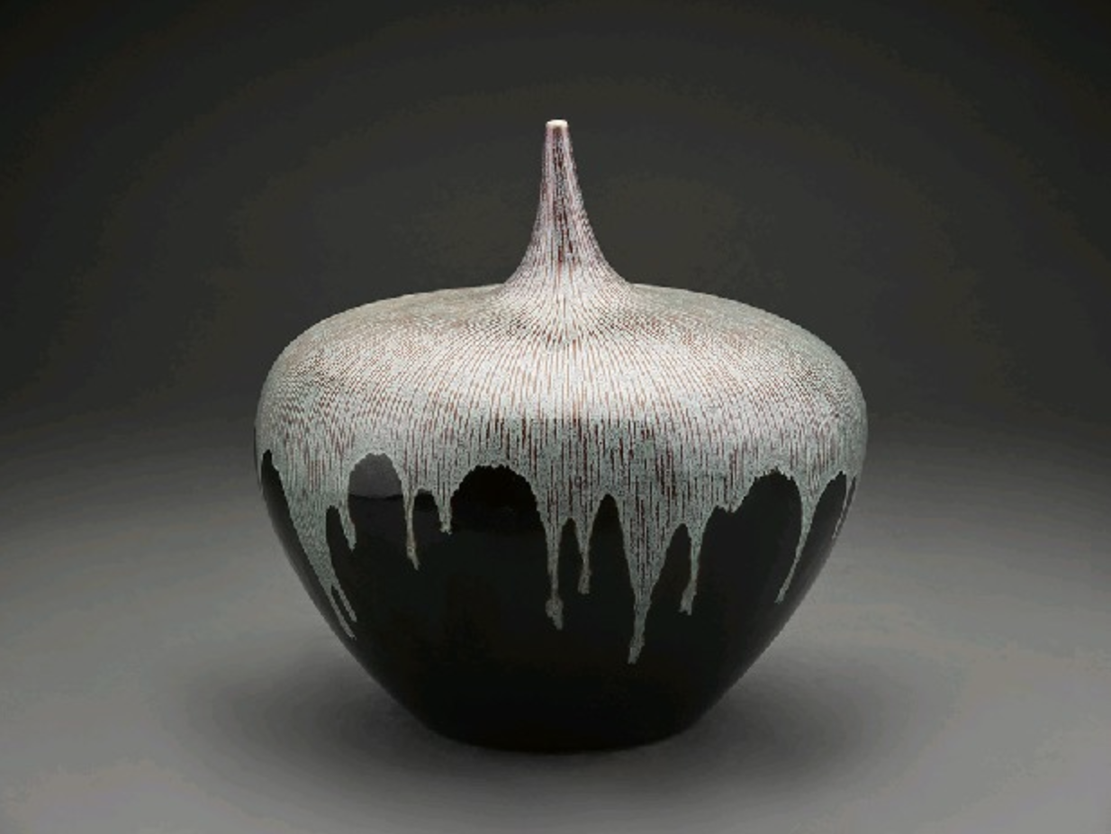 A modern, artistic ceramic vase with a textured, cream-colored top that drips down into a black base.