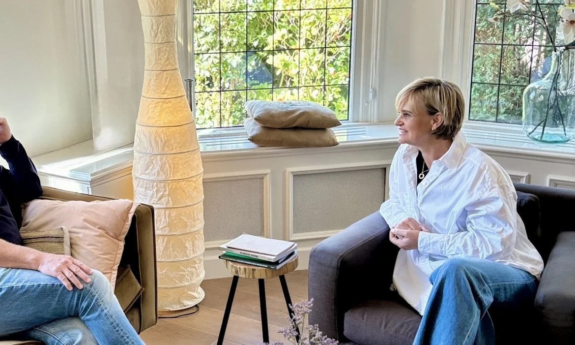 Een coach en een coachee voeren een coach gesprek in een huiselijke coachruimte aan huis met een prettige sfeer