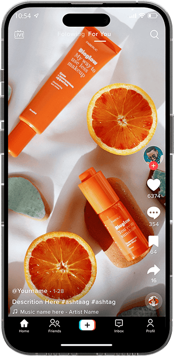 Two orange skincare products alongside two slices of orange and an orange-colored makeup sponge on a white surface.