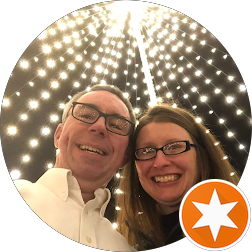 A smiling couple taking a selfie under a large, star-shaped light display.