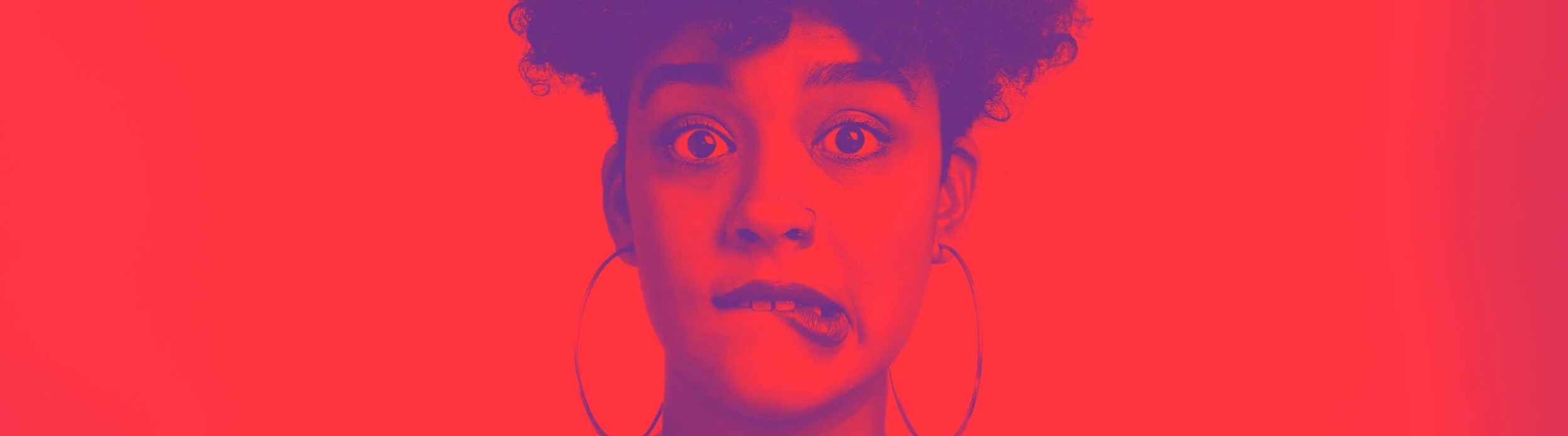 Close-up of a woman with curly hair, wearing large hoop earrings, and making a surprised or confused facial expression against a red background.