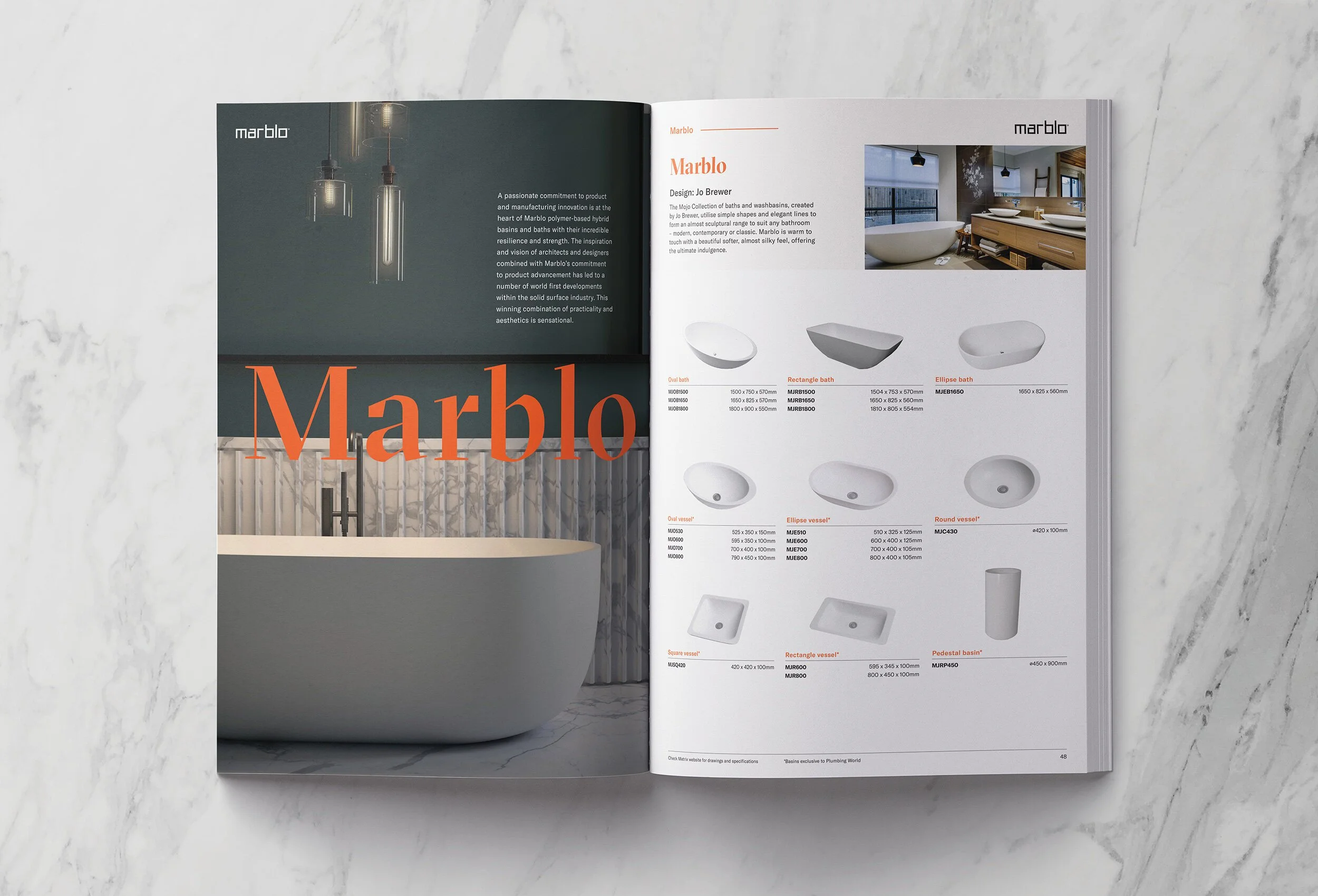 Open magazine displaying bathroom fixtures and design ideas with a marble background.