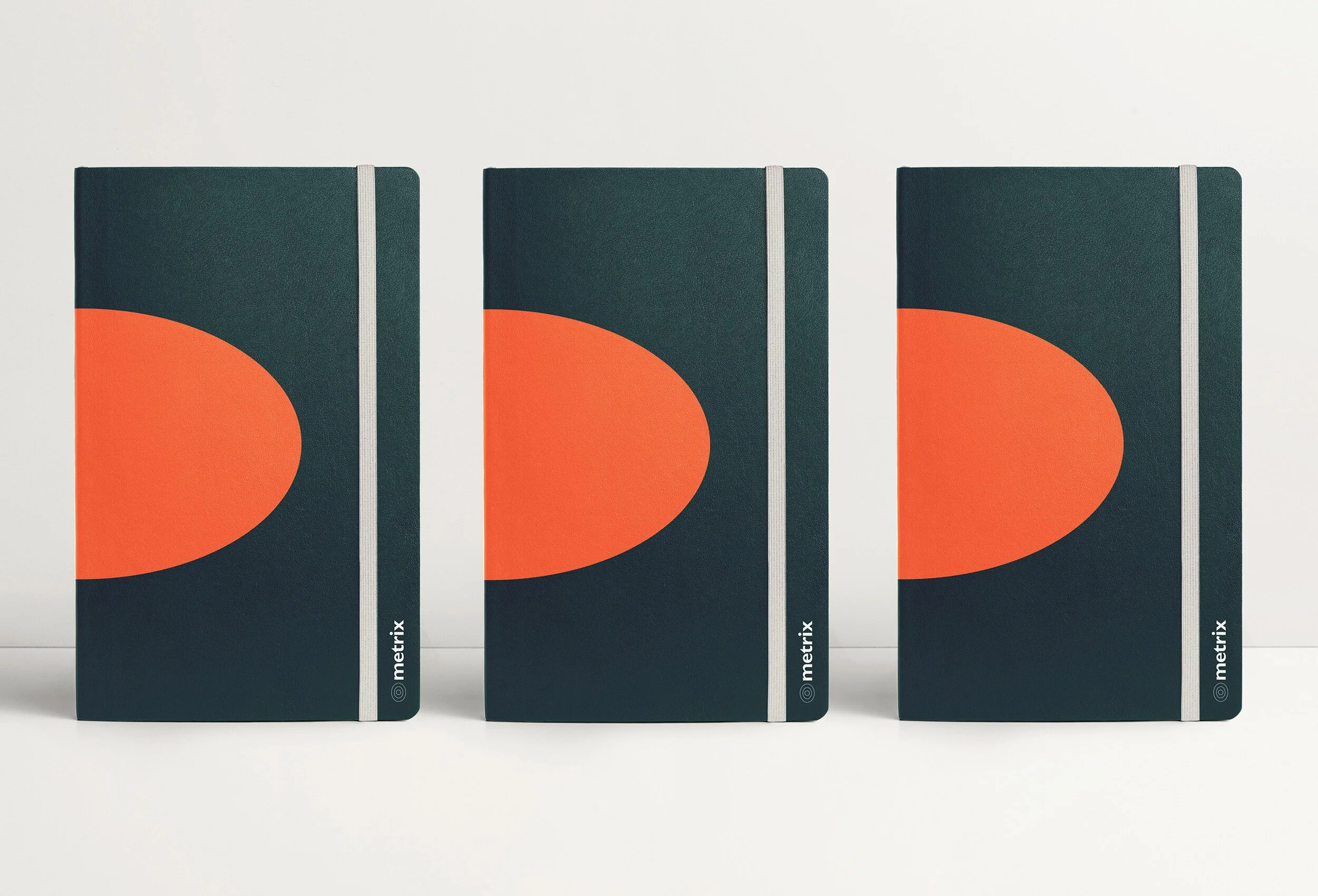 Three black notebooks with orange semi-circles on the cover, standing upright against a white background.