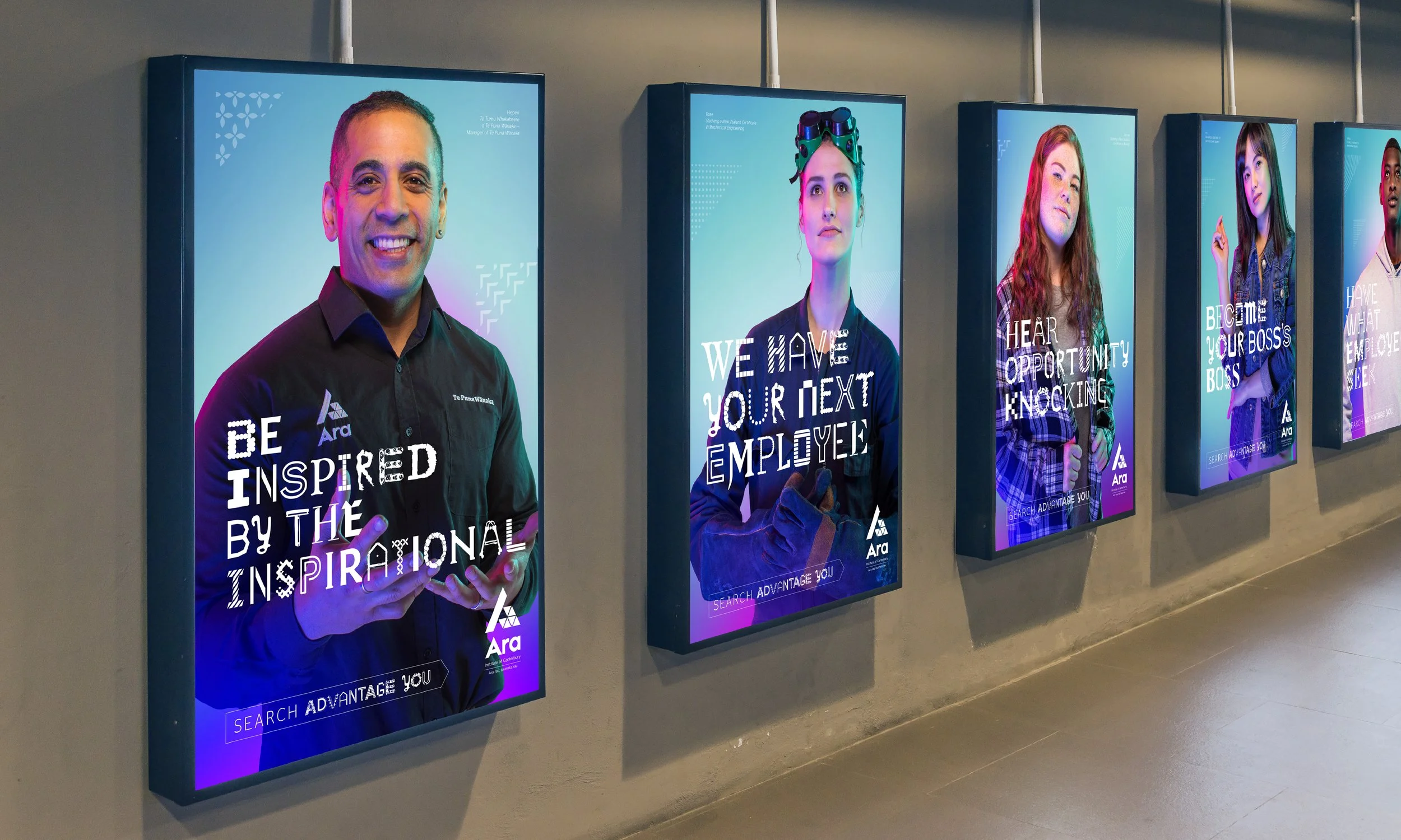 Four digital posters on a wall featuring portraits of diverse individuals with motivational messages about employment and inspiration, with a company logo at the bottom of each poster.