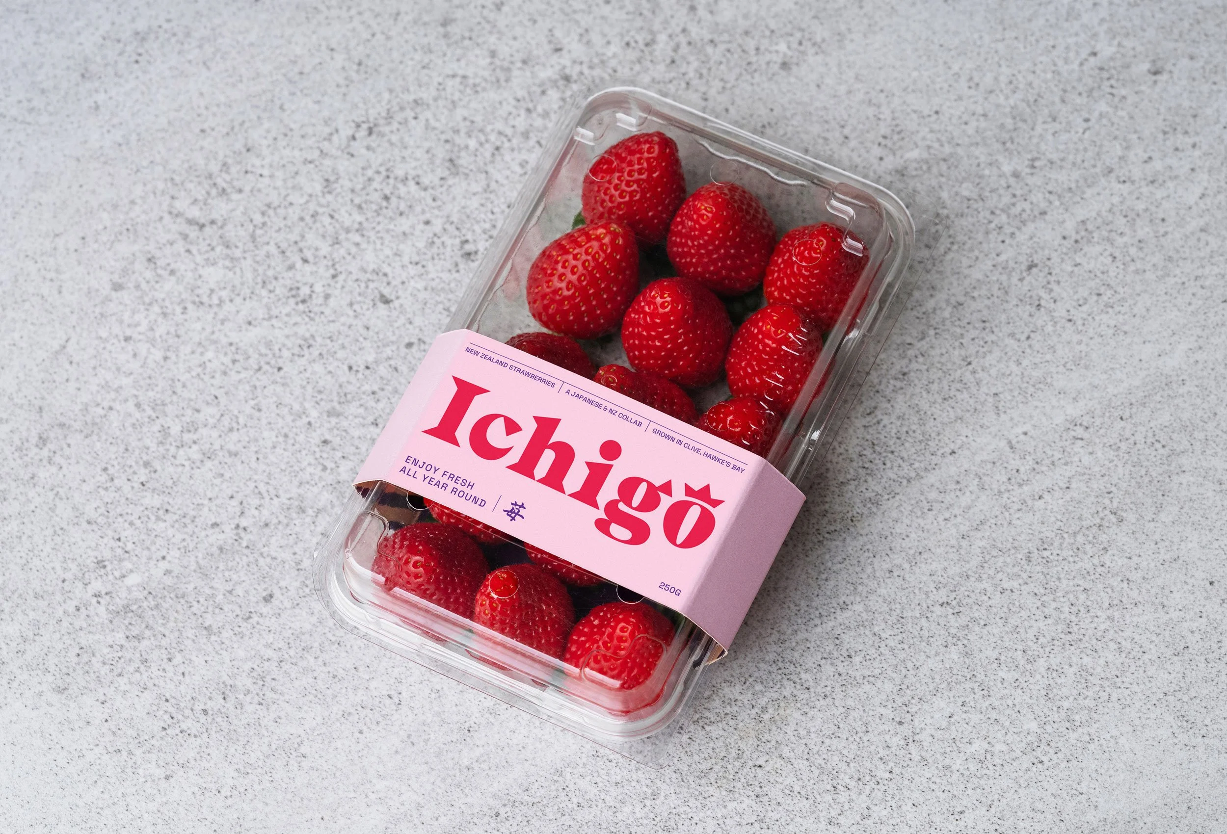 A clear plastic container of fresh red strawberries on a gray speckled surface.