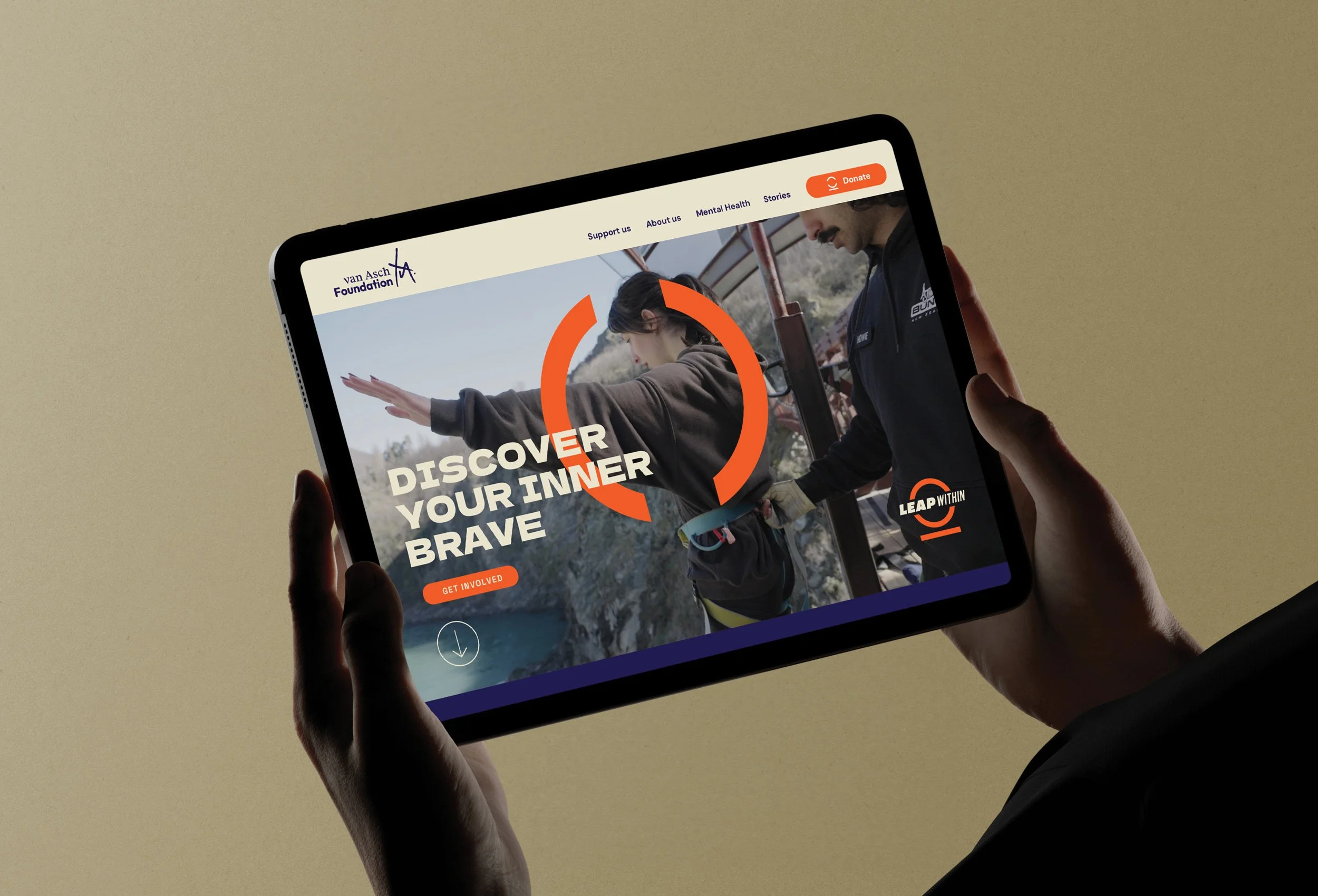 Person holding a tablet displaying a website for a foundation, with a woman and a man outdoors, suggesting outdoor activity or adventure.