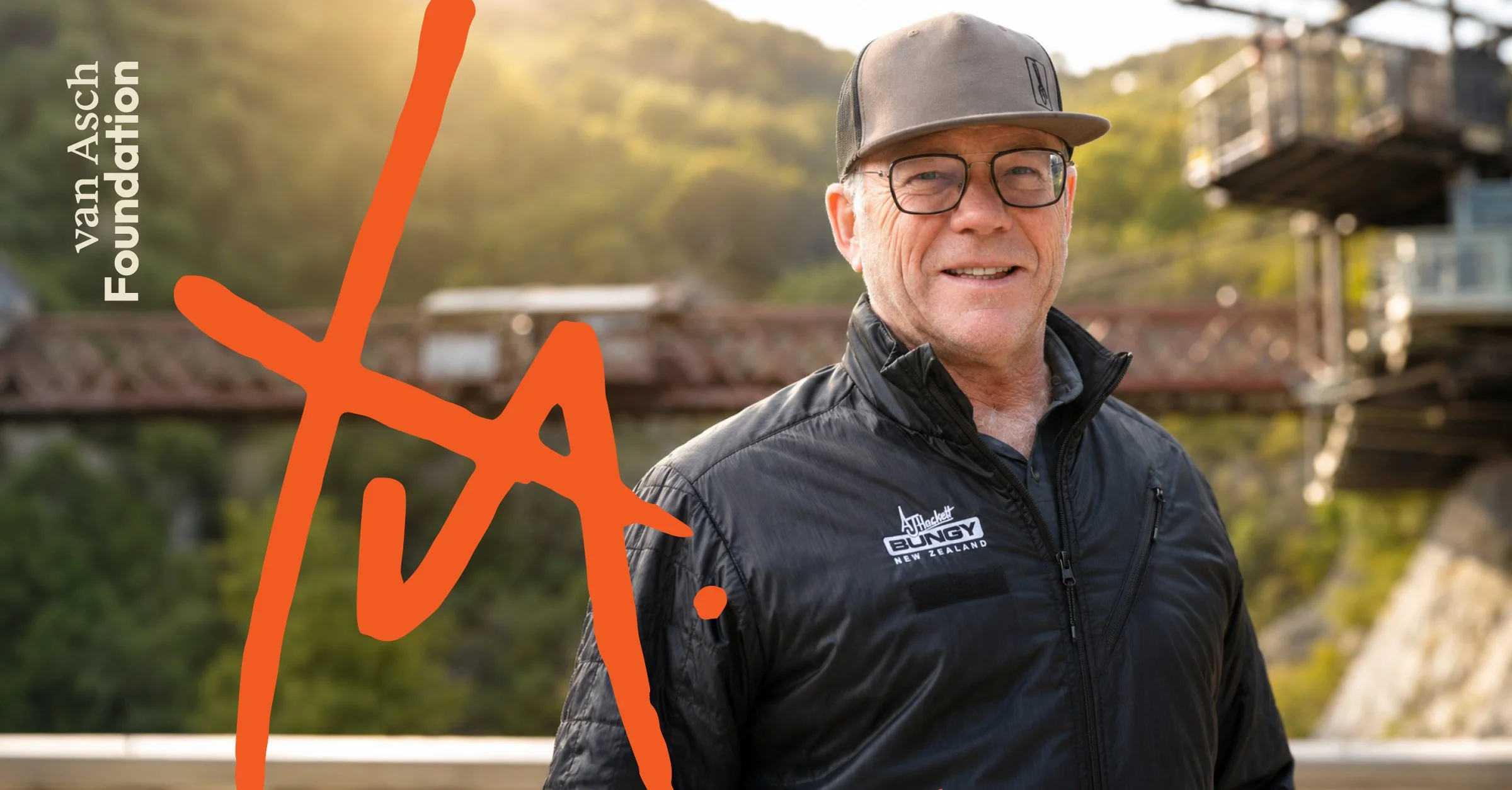 A man wearing glasses, a gray cap, and a black jacket with a logo stands outdoors with a blurred background of trees and a bridge. There is an orange illustration and text overlay that says "Van Asch Foundation".