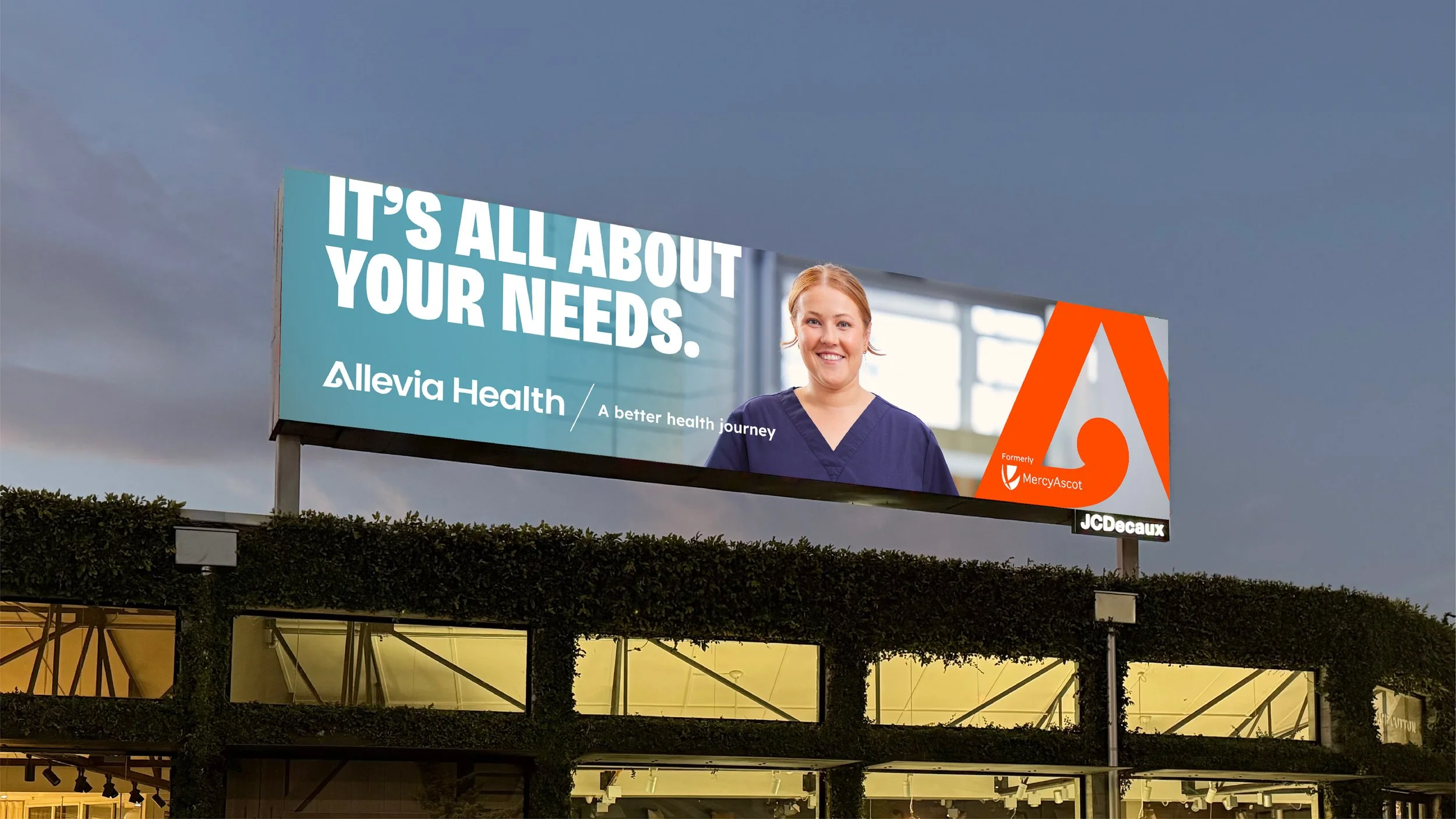 Billboard advertising Allevia Health with a smiling woman in scrubs and the message 'It's all about your needs.' The billboard mentions MercyAscot and JCDecaux branding.