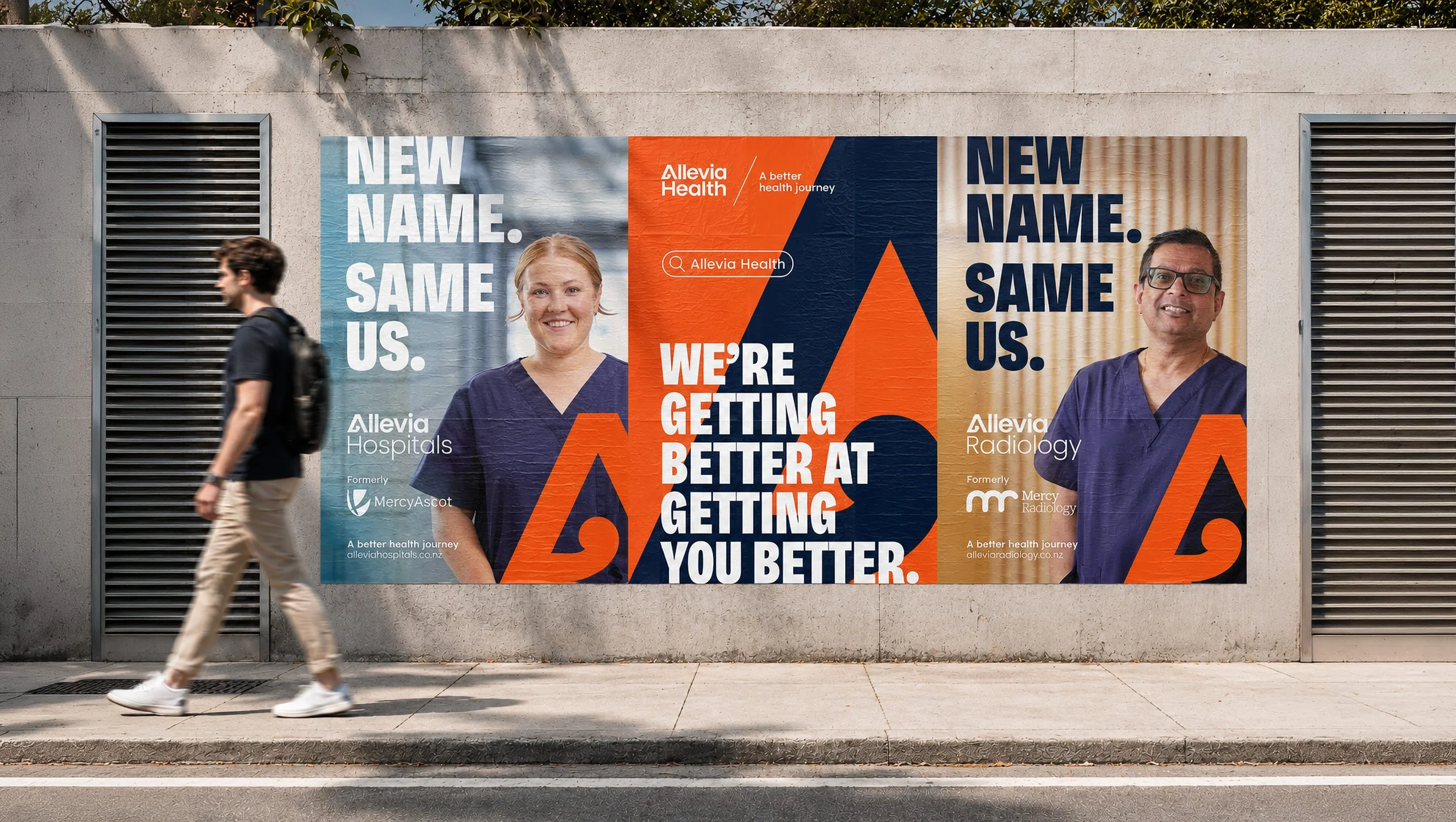 A large advertisement for Allevia Health on a city wall featuring images of two healthcare professionals, with bold text that reads 'New Name. Same Us. We're Getting Better at Getting You Better.' The background has geometric orange and blue shapes, and the advertisement mentions Allevia Hospitals and Radiology, formerly MercyAscot and Mercy Radiology.