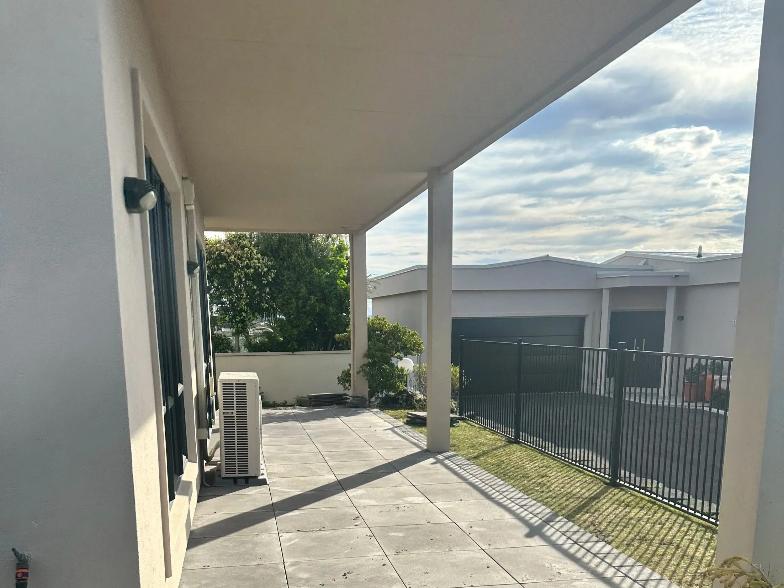 Concrete paved patio with black railing and custom decorative black metal screen with botanical cutouts