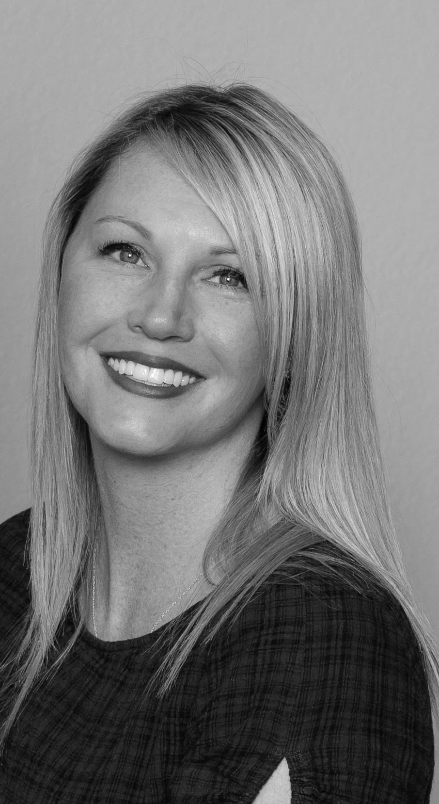 Black and white portrait of a woman with long, straight hair smiling at the camera.