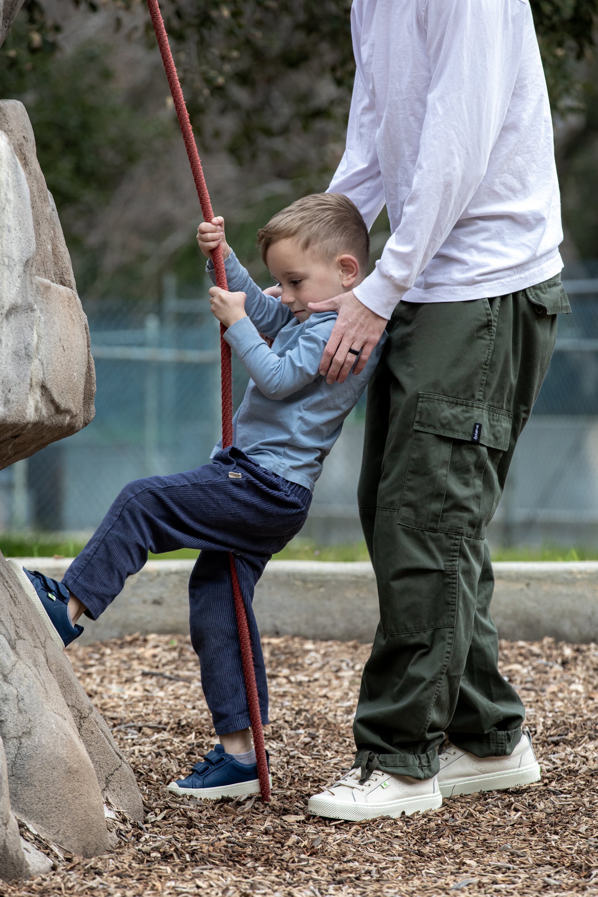 Tyler helping Azai climb rope at playground.JPG