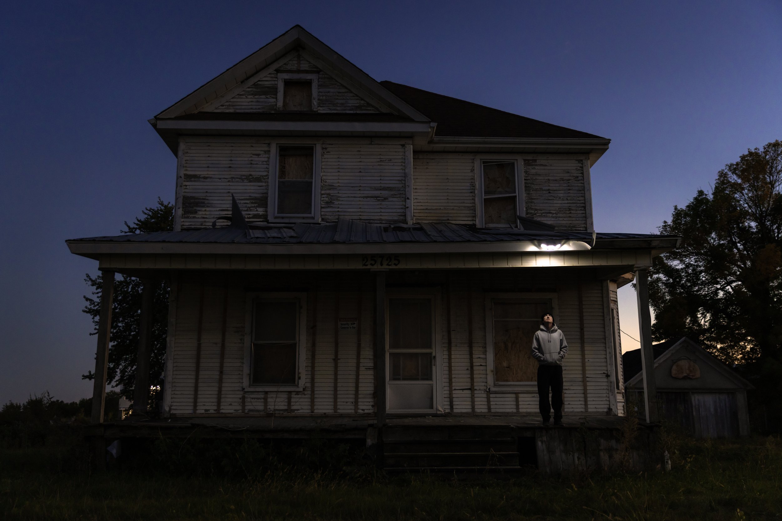 Tyler standing under light on porch at abandoned house.JPG
