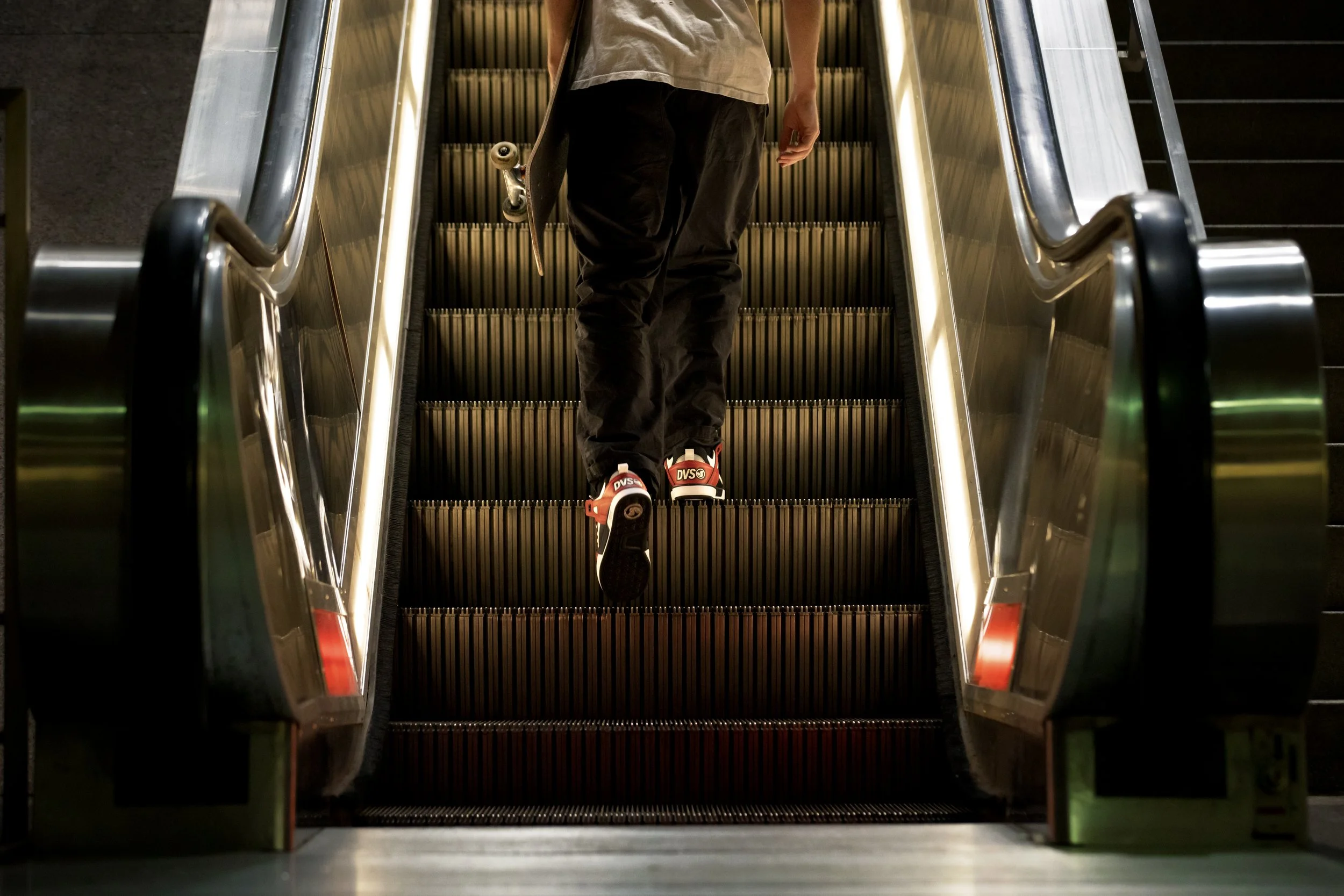 Tyler walking up escalator in red:white:black Comanche LTs product photo.JPG