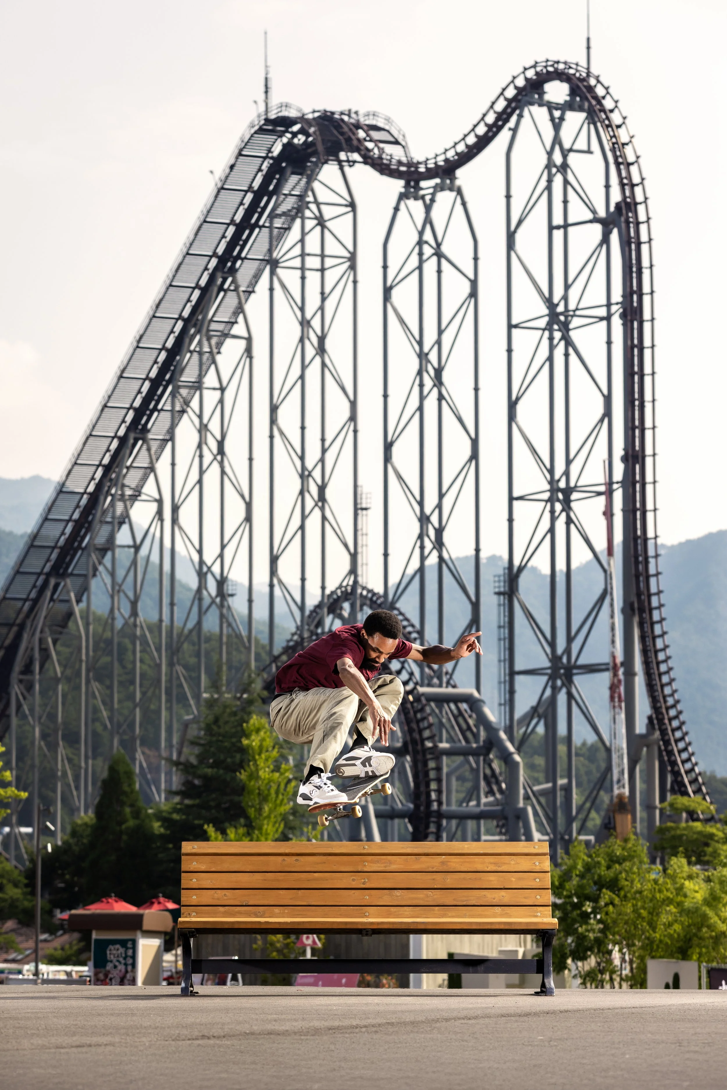 Timmy ollie over bench in front of rollercoaster.JPG