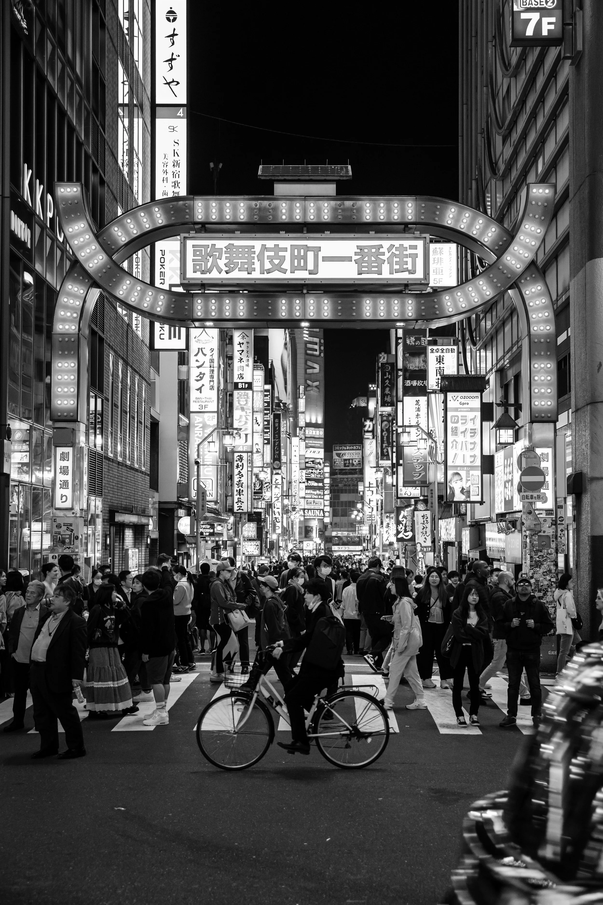 Person riding bicycle under sign in Shinjuku Square.JPG