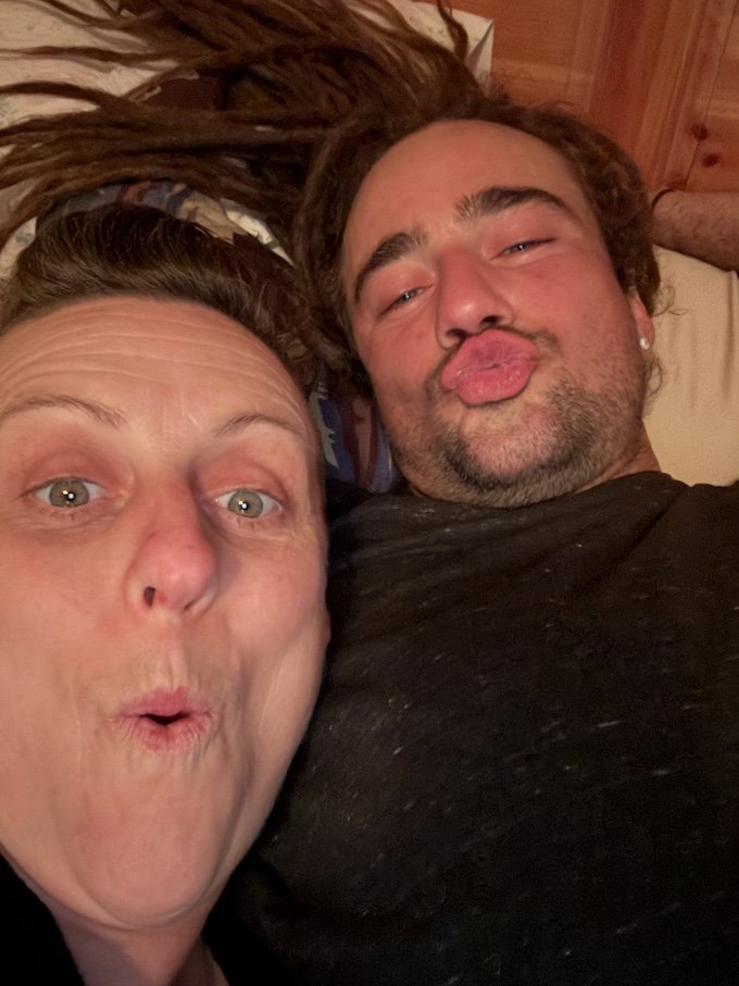 A woman and a man lying down on a bed, making funny faces at the camera.