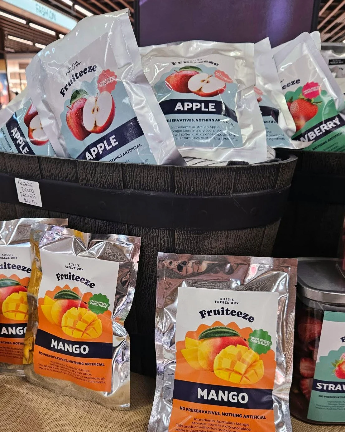 Assorted Bags of freeze dried fruit, including apple and mango, displayed on a store shelf.