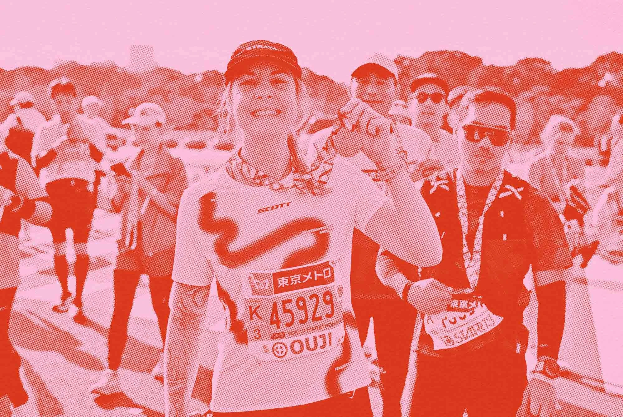A woman holding a medal at the end of a race surrounded by people and runners.