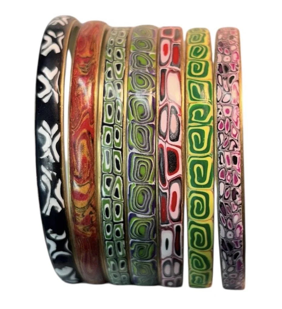 Set of six colorful glass bangles with intricate patterns arranged in a row.