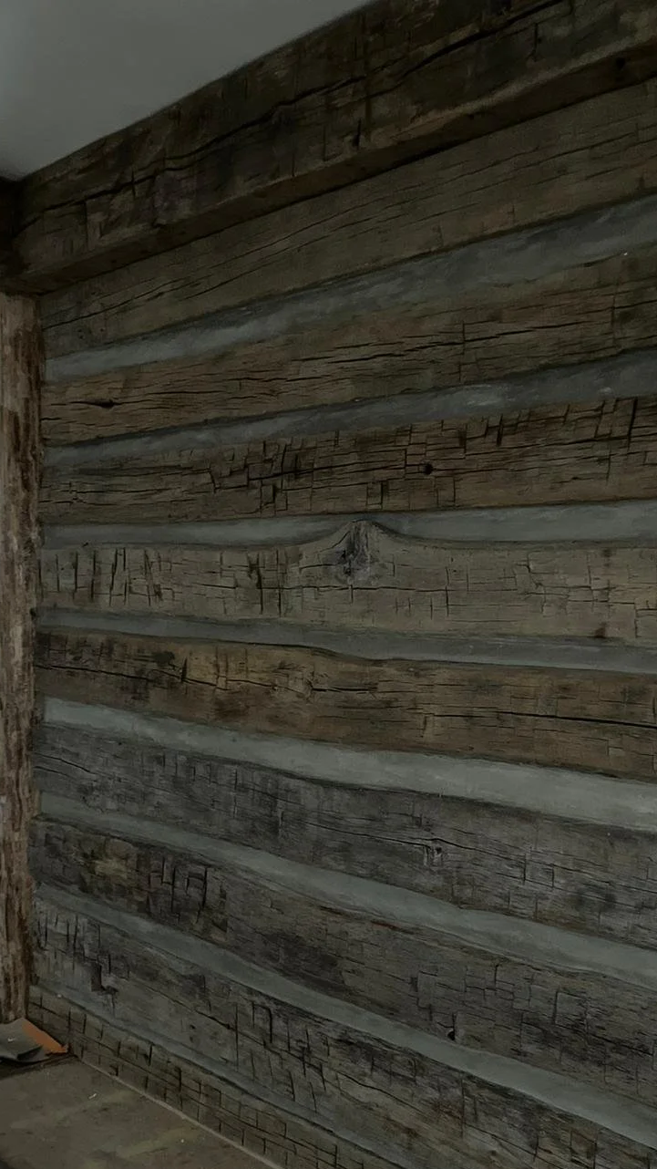 Close-up of a weathered, wooden interior wall with horizontal planks showing cracks and grain patterns.