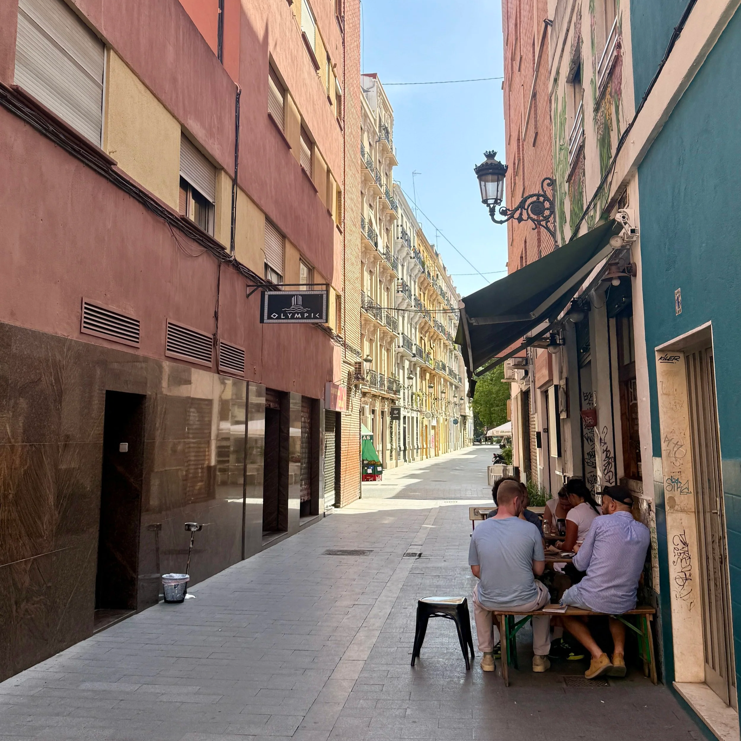 A narrow street with people sitting outside at a restaurant in Ruzafa neighborhood in Valencia, Spain
