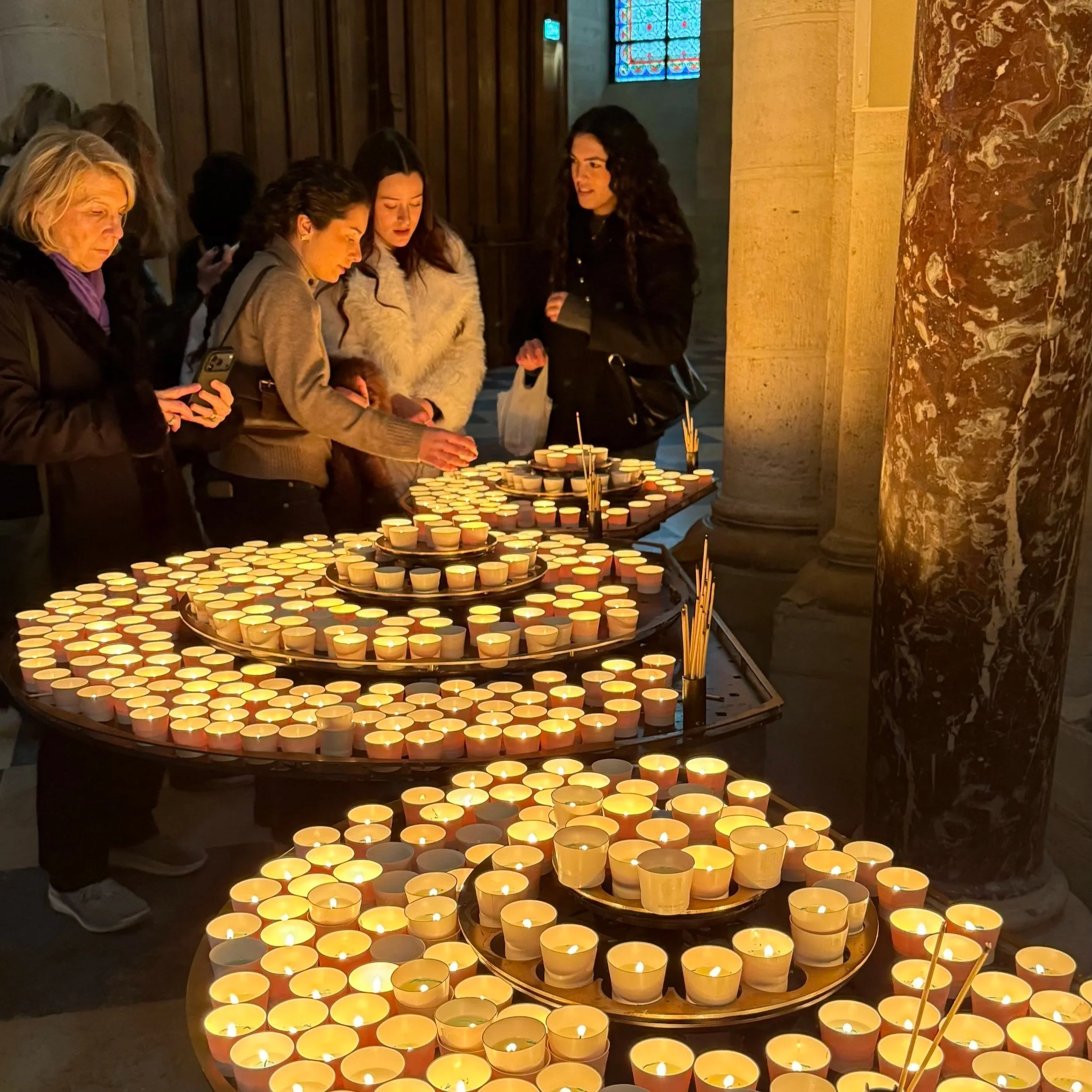 People lighting candles inside Notre Dame Cathedral in Paris, France