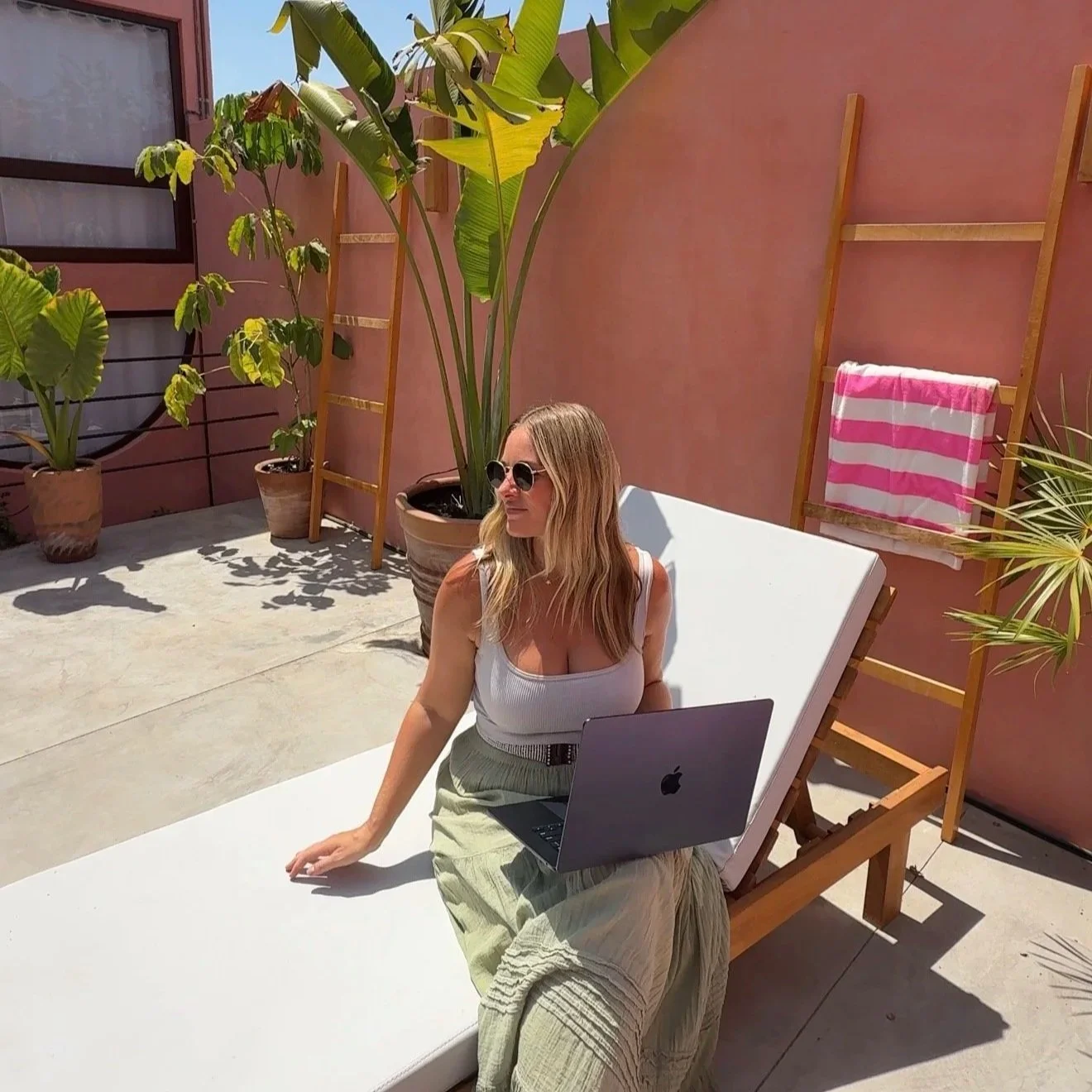 Megan sitting on a sunbed with laptop doing remote work at a digital nomad in Puerto Escondido, Mexico