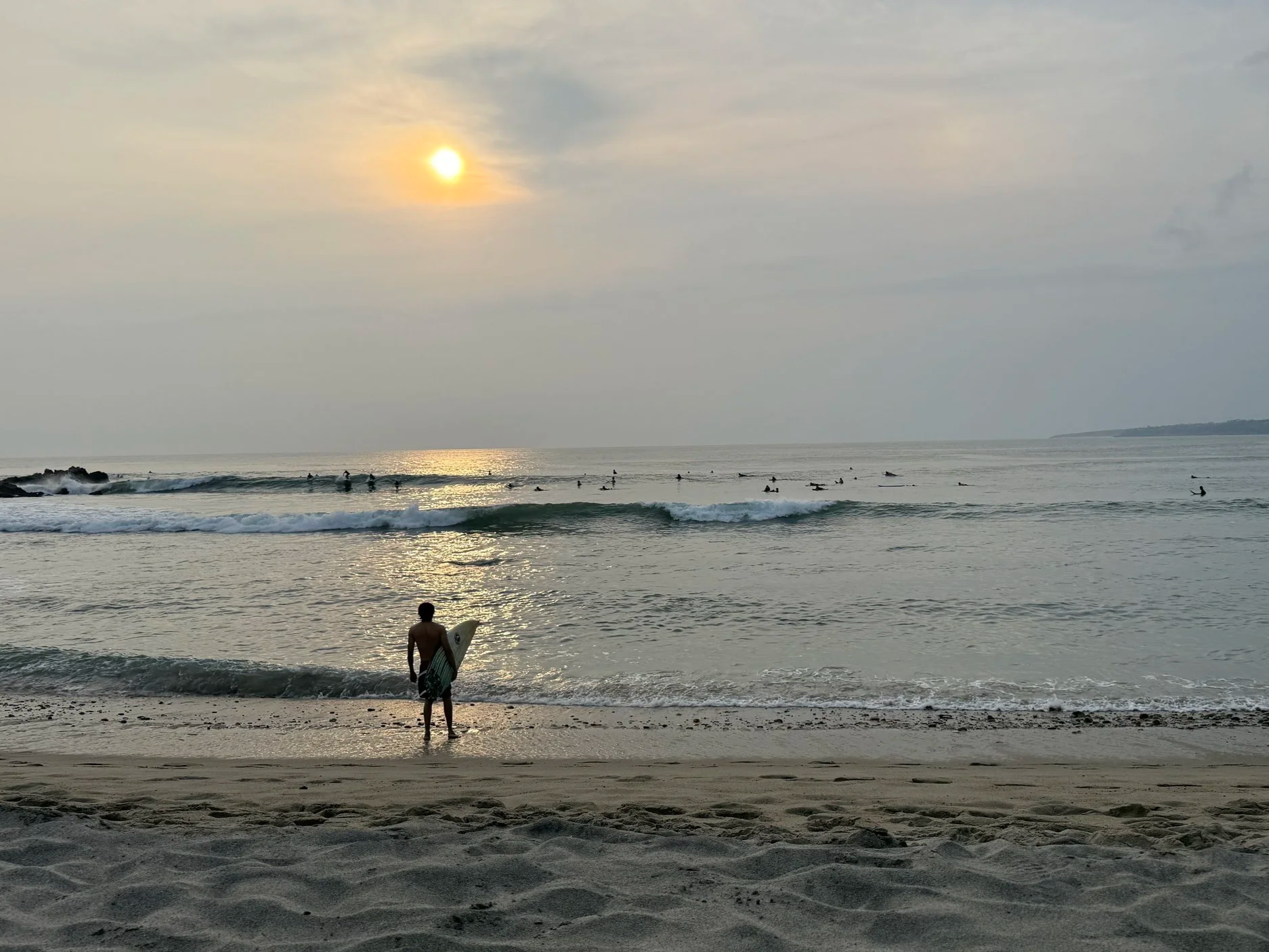 Surfer stands in front of the Pacific Ocean in Puerto Escondido, Mexico in the late afternoon sun