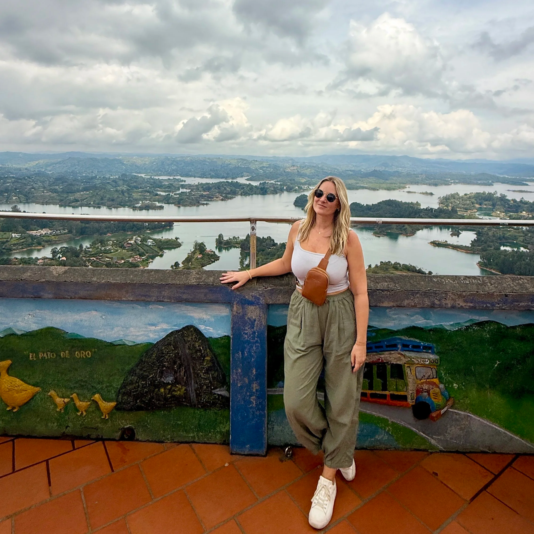 Megan at the top of La Piedra del Piñol in Guatapé, Colombia with a view of the reservoir and mountains