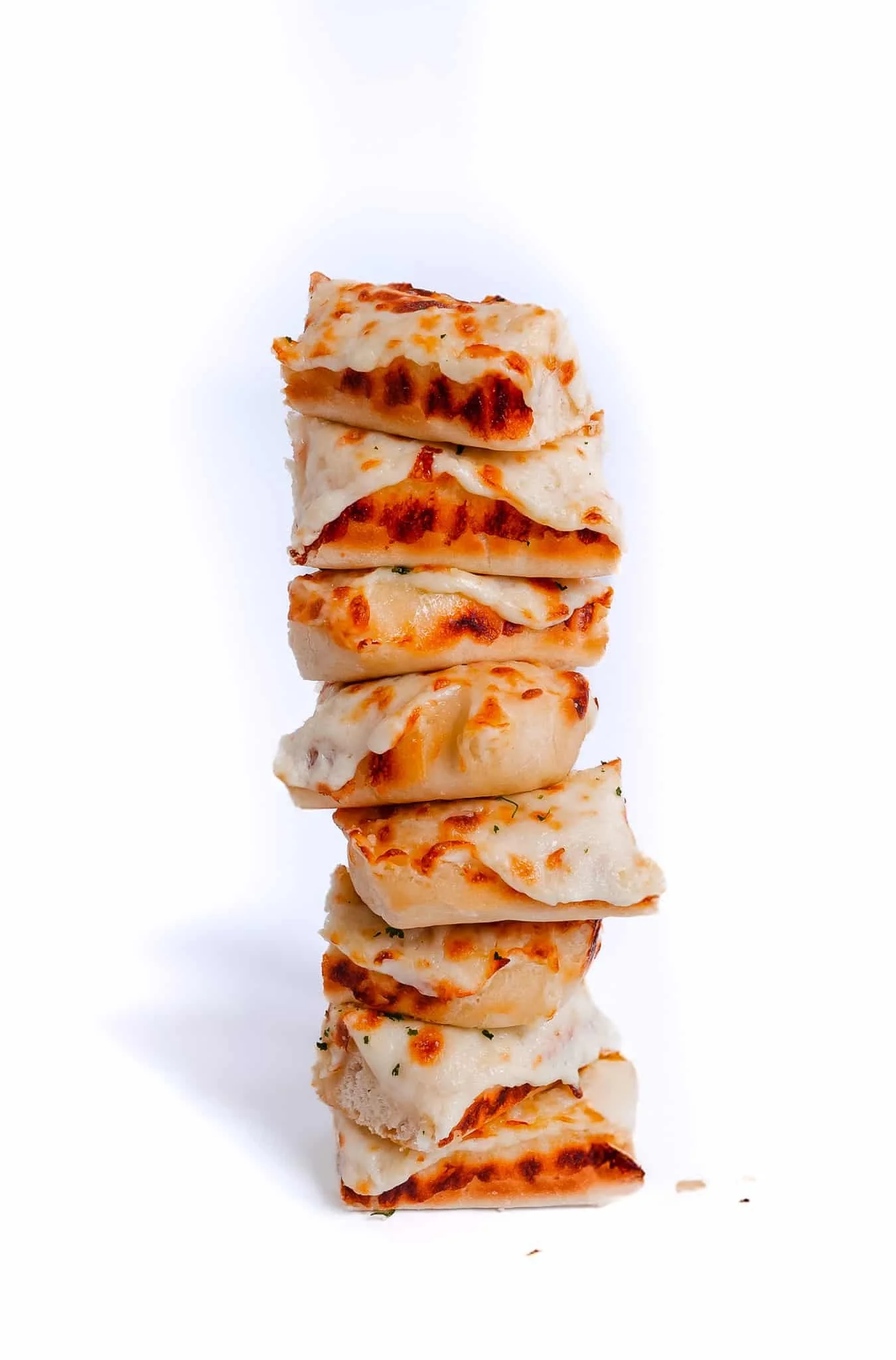 Stack of several slices of cheese pizza with melted cheese and a golden-brown crust against a white background.