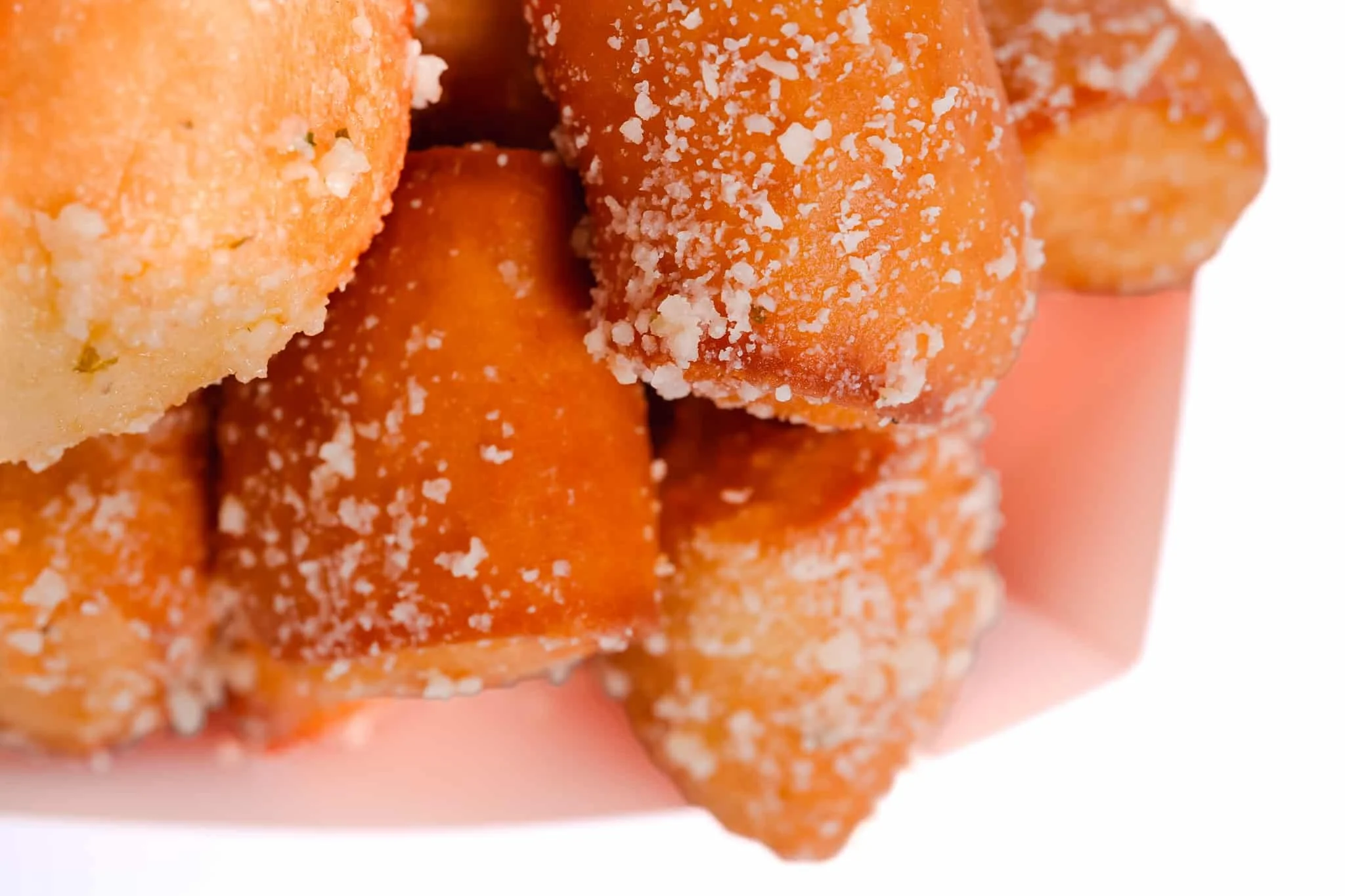 Close-up of orange-colored croquettes coated with white salt.