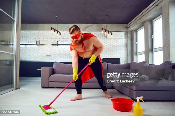 Man is cleaning the floor with a pink mop in a modern living room.