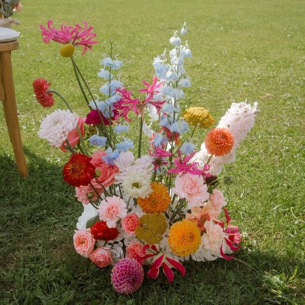 Colorful bouquet of various flowers placed on grass outdoors.