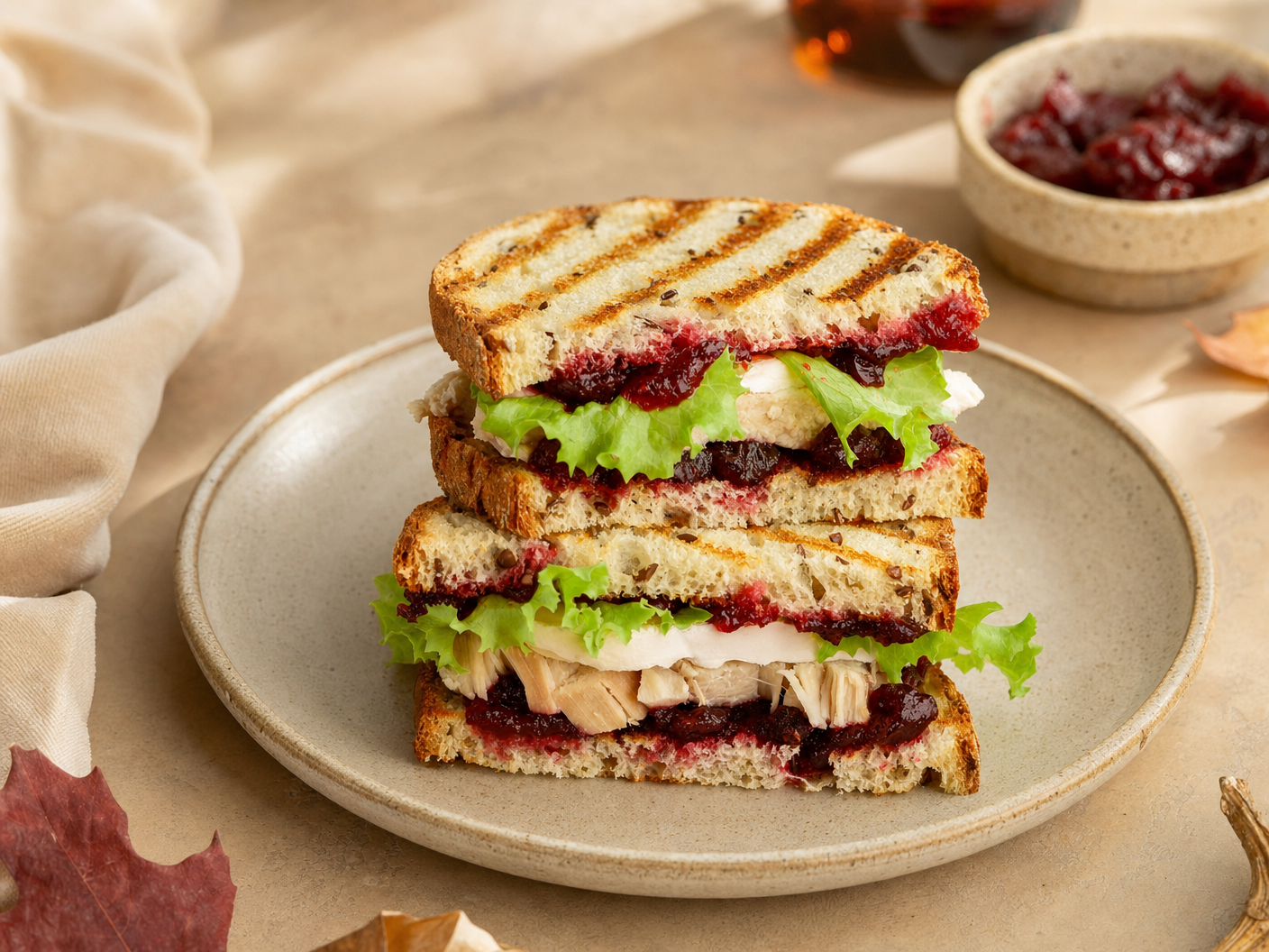 Grilled panini halves stacked with sliced turkey, lettuce, white cheese and guava spread, with a bowl of fruit preserves behind
