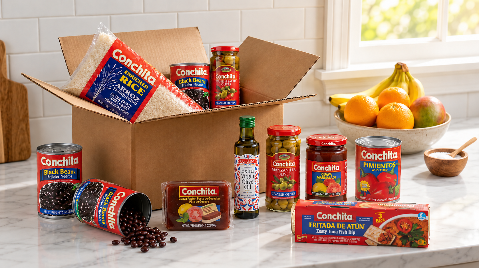 Open shipping box of Conchita groceries including enriched rice, black beans, olives, extra virgin olive oil, guava paste, guava marmalade, pimientos and tuna dip