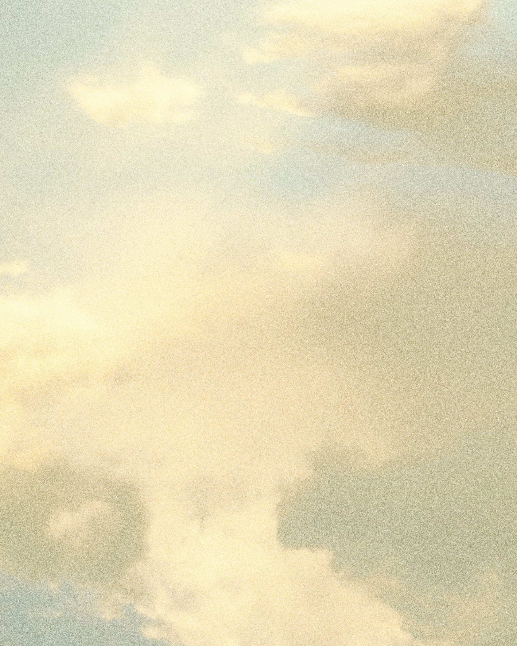 A view of a cloudy sky during sunset with soft, light clouds and a gradient of warm colors from yellow to light brown.