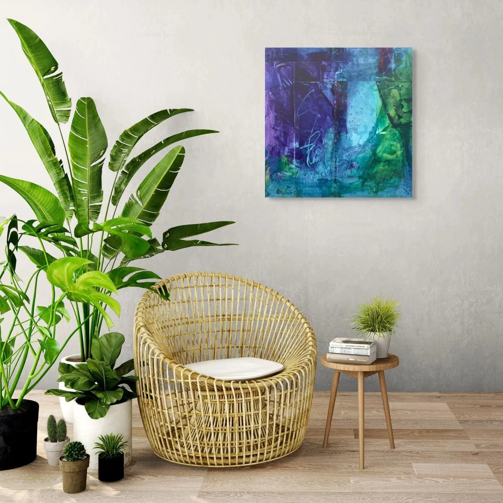 A cozy corner with a rattan chair featuring a white cushion, a small wooden side table with plants and books, large green potted plants, and a colorful abstract painting on a neutral wall.