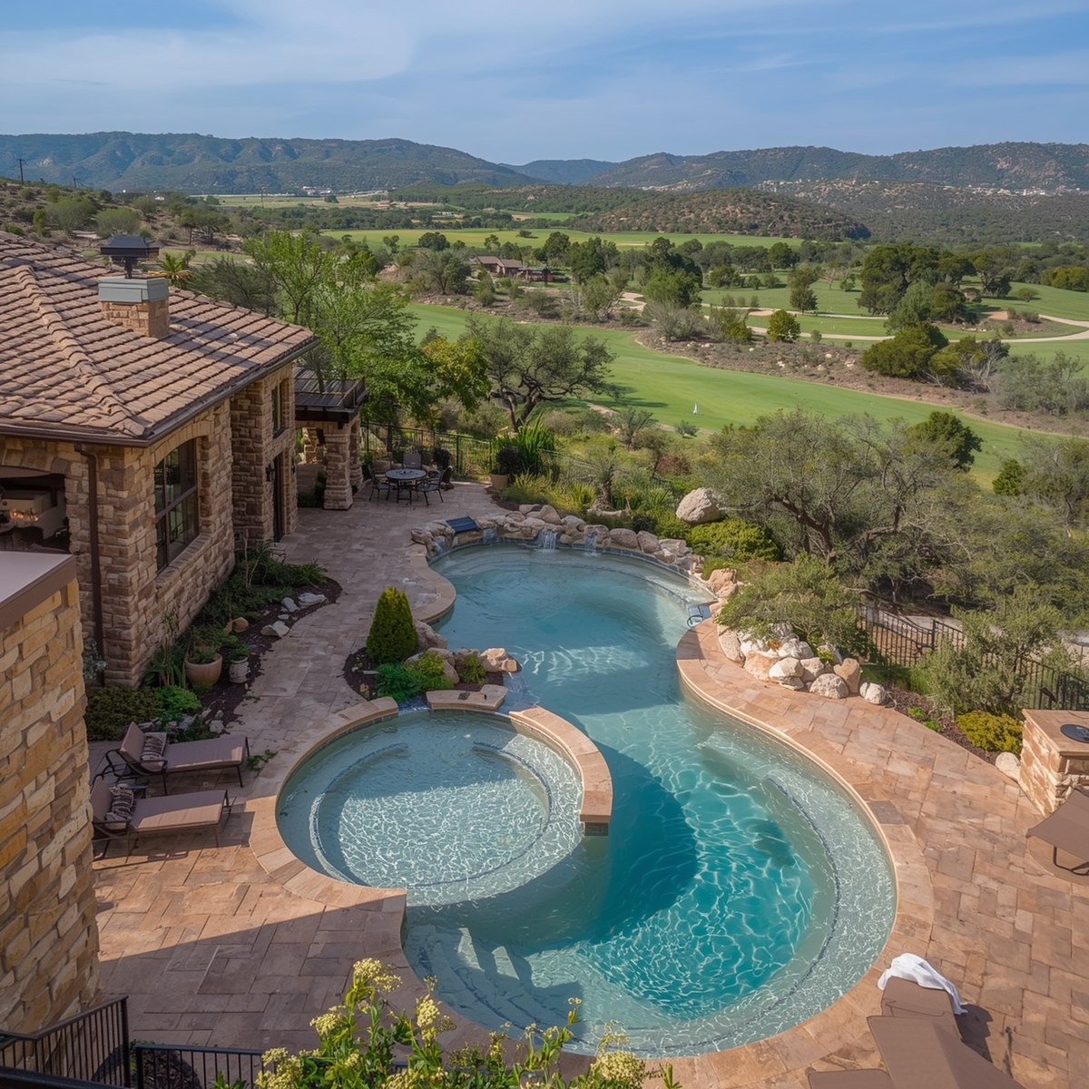 A backyard with a winding swimming pool and hot tub, patio furniture, and a view of a green landscape with trees, fields, and mountains in the distance.