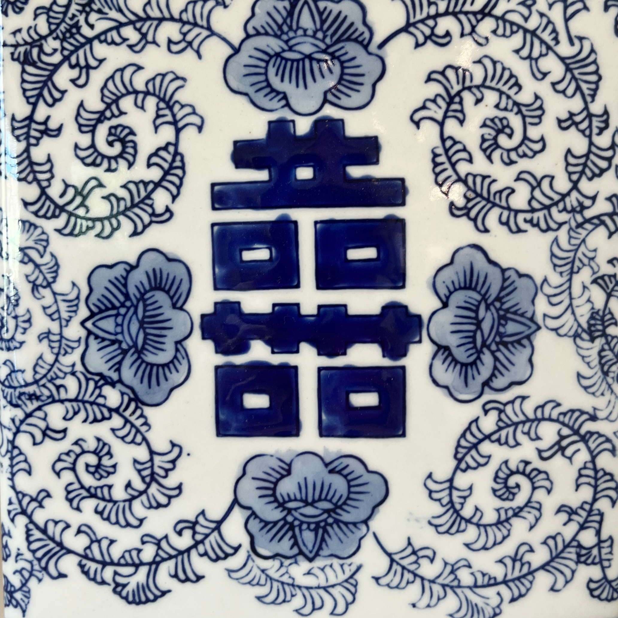Close-up of a blue and white floral-patterned ceramic surface with Chinese characters in the center.