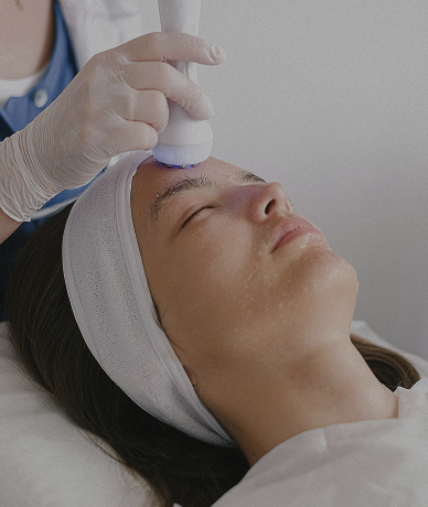 Paciente recebendo tratamento facial com aparelho em clínica de estética.