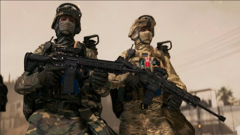 Two soldiers in camouflage gear and helmets, wearing face coverings, holding rifles, standing outdoors during daytime.