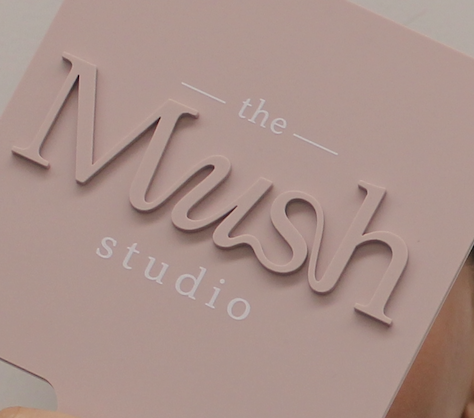 A pink sign with raised lettering that reads "the M u s h studio".