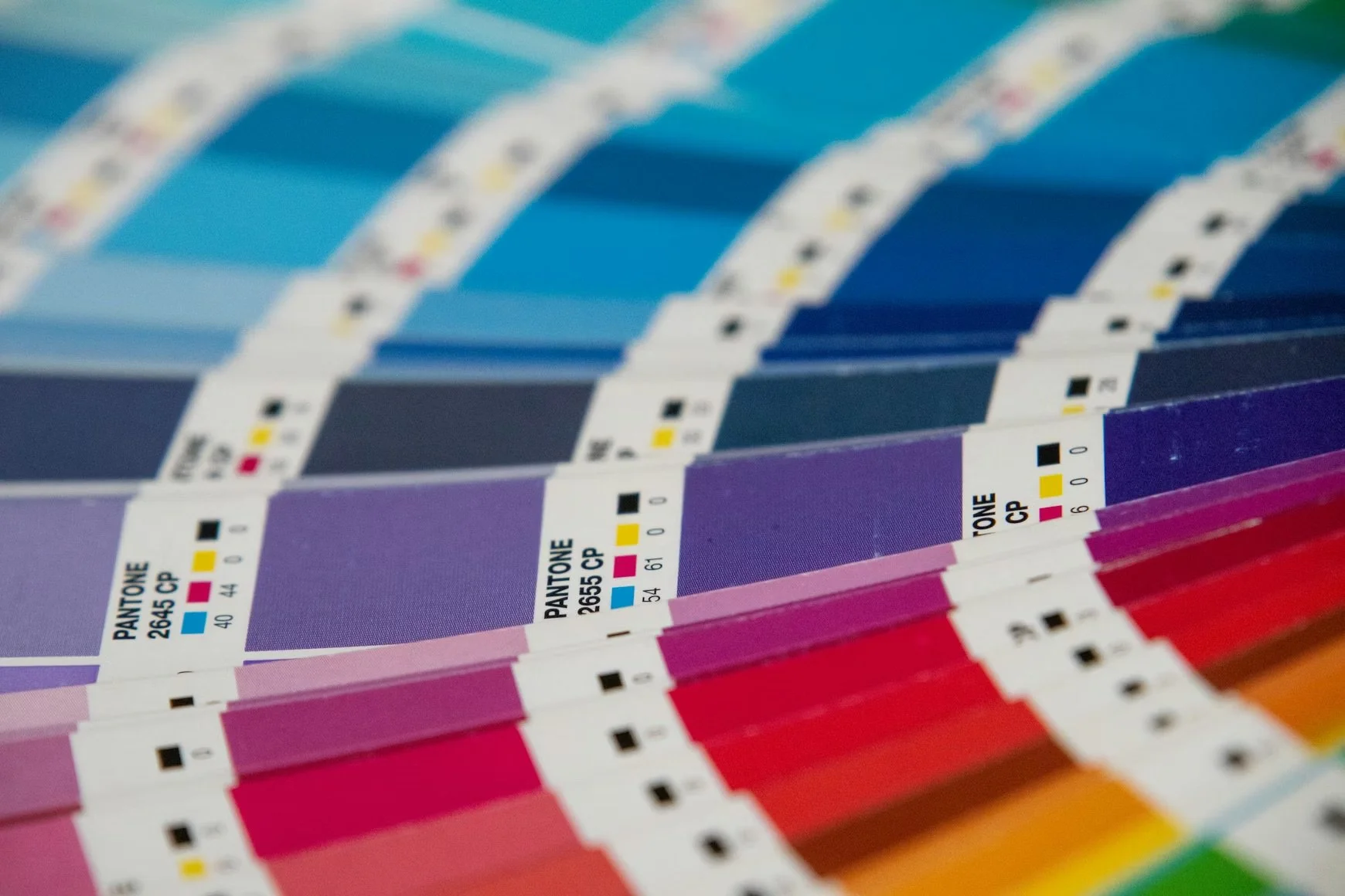 Close-up of color swatch book showing various shades of blue, purple, red, and orange with Pantone color codes.