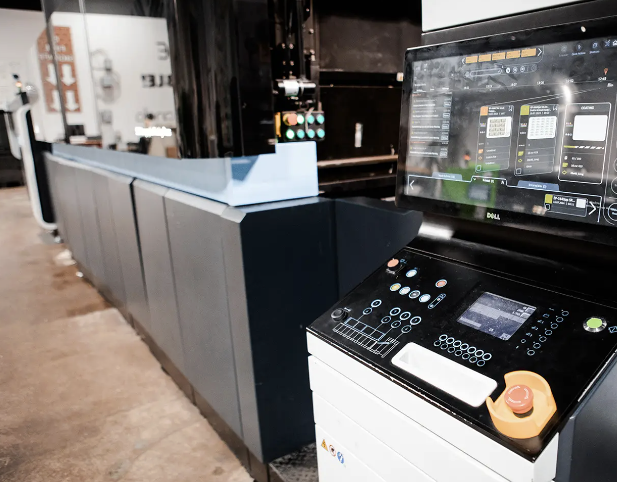 Industrial machine with control panel and screen in a warehouse or factory setting.