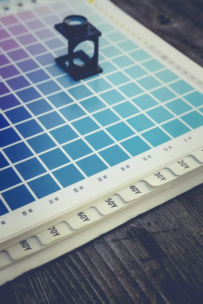 Color calibration chart with a small black lens holder and a lens on top, placed on a table.